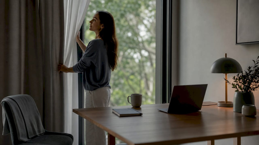 Woman adjusting blackout curtains in bedroom